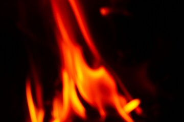 Wooden logs are burning in the fireplace. Tongues of flame on a dark background.