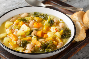 Italian Bean and Vegetable Soup Zuppa alla Frantoiana closeup on the bowl on the wooden board. Horizontal