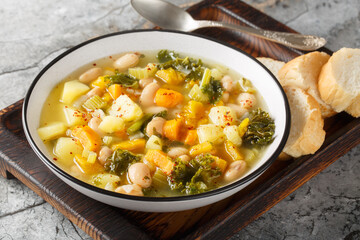 Vegetable soup with beans, potatoes, pumpkin, kale, carrots, onions and celery close-up in a bowl on the table. Horizontal