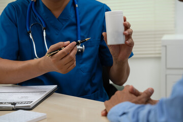A male doctor sits and works at the table, explaining the urinary system and penile health to...