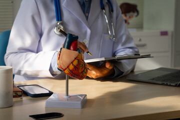A male doctor sits at a desk in the heart clinic, consulting online and giving advice. The vascular surgery clinic offers an electrocardiogram service with modern technology and expert care.