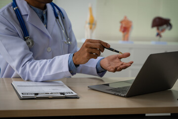 A male doctor sits at a desk in the heart clinic, consulting online and giving advice. The vascular surgery clinic offers an electrocardiogram service with modern technology and expert care.