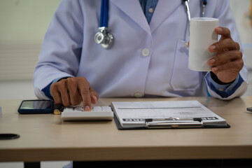 A male doctor sits at a desk in the heart clinic, consulting online and giving advice. The vascular surgery clinic offers an electrocardiogram service with modern technology and expert care.