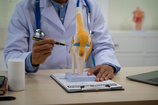 A male doctor in leather works at the table in the bone disease clinic, addressing issues such as cervical spine disease, osteoporosis, herniated discs, and more with expert care.