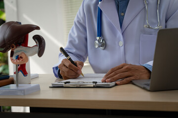 A male doctor sits at a table in a liver disease clinic, giving online advice on hepatitis A, D, E,...