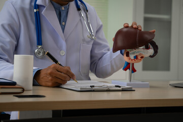 A male doctor sits at a table in a liver disease clinic, giving online advice on hepatitis A, D, E,...