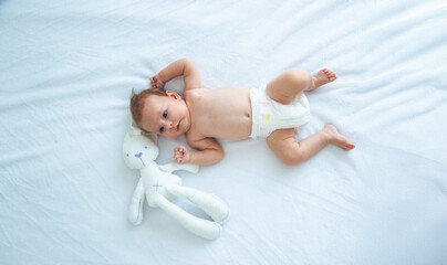 A newborn baby lies on a white background with a soft toy bunny. baby