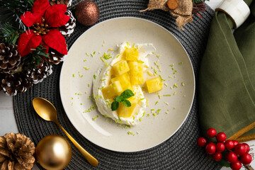 Delicious dessert with fresh pineapple and whipped cream on a table with Christmas decoration.