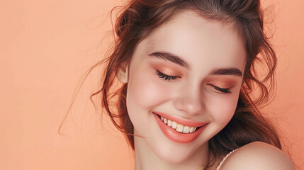 Naklejka premium Smiling beautiful woman model with makeup against studio peach background