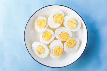 several halved boiled eggs in a plate on a blue background