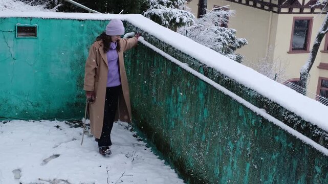 Attractive woman pushing off the snow from a railing in an abandoned swimming pool. Insecure what to do, everyday problems. White Christmas season, adult playing with falling snow in winter wonderland