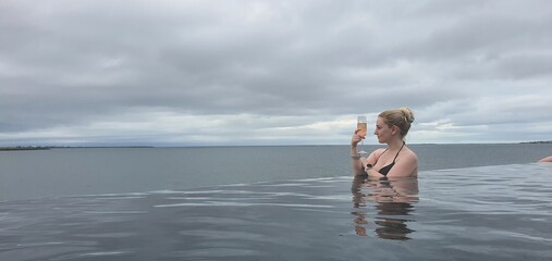 blond female tourist bathing in an endless hot tube on a cloudy day