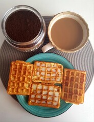 Cup of coffee with waffles on a white wooden background.