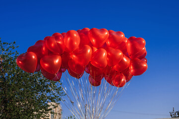 many red balloons in the shape of a heart on the background of blue sky