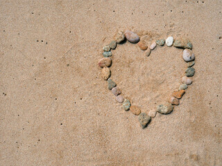 Set of colorful pebbles forming a shape on beach sand background © Roberto