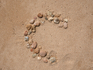 Set of colorful pebbles forming a shape on beach sand background
