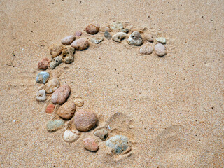Set of colorful pebbles forming a shape on beach sand background