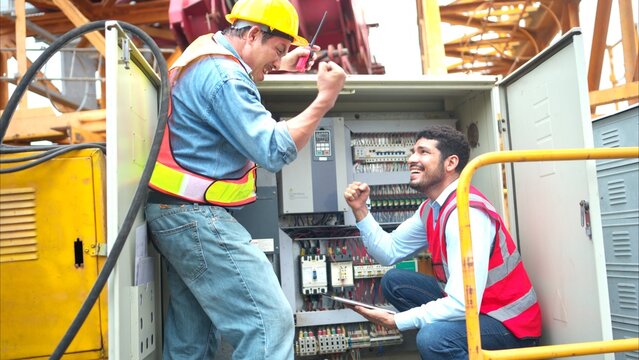 Bothe of electrical engineer inspects the electrical control board of a crane before putting it to use on a construction site