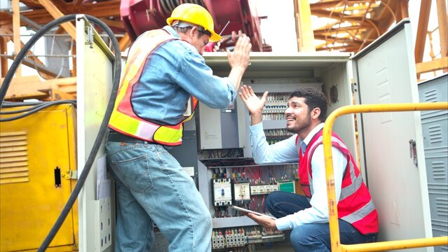 Bothe of electrical engineer inspects the electrical control board of a crane before putting it to use on a construction site