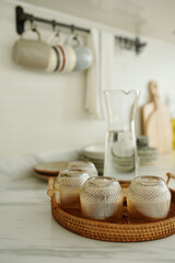 Close-up of wicker tray with clean glasses on kitchen table