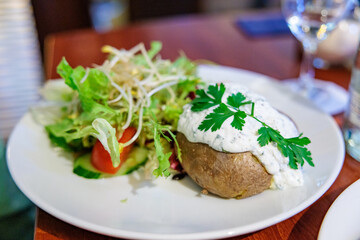 Baked Potato Topped with Crème Fraîche and Fresh Salad in a Restaurant Setting