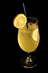 Limoncello Spritz, in a tall glass with a straw and orange slices, against a black background.