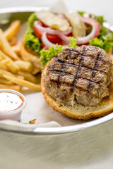 beef burger hamburger on a plate with salad and french fries and sauce on the side