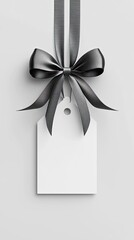 Elegant black gift tag with ribbon and bow on a grey background