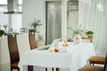 Dining table in the dining room with laptop and tea