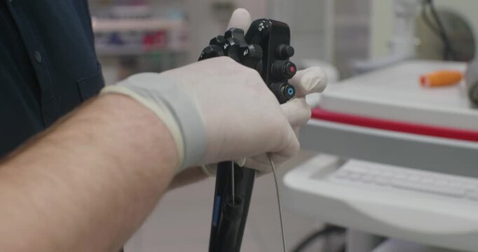 The doctor holds the gastroscope control panel in his hand and deftly operates it. Close-up of the gastroscope control panel in the doctor's hand. An experienced doctor works with a gastroscope.