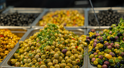 Black, yellow and green olives, marinated in olive oil with herbs and spices, market stalll at the weekly market in Rotterdam. Mediterranean vegetables, healthy food.