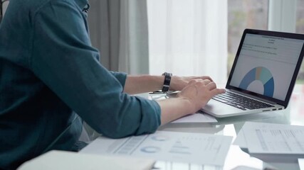 Professional working at laptop with data analysis charts. Businessman analyzing statistical data on a laptop next to business reports. Business concept