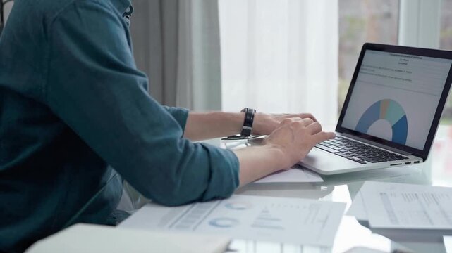 Professional working at laptop with data analysis charts. Businessman analyzing statistical data on a laptop next to business reports. Business concept