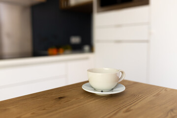 Empty ceramic mug mockup product display with blurry kitchen background.