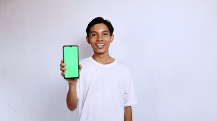 smiling asian man young man wearing white shirt showing green screen mobile phone for advertising