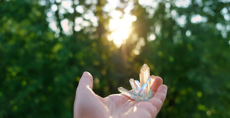 aura quartz crystal in hand outdoor, natural forest background. Esoteric spiritual practice....