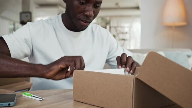 Tilt up shot of cheerful African American man being glad about getting new pair of leather shoes as parcel at home