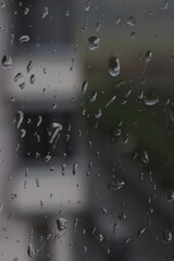 Raindrops on a window with blurred background, evoking feelings of nostalgia, calm, and reflection