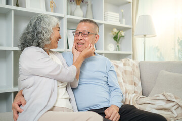 Fototapeta premium Affectionate elderly couple sharing a tender moment on a cozy sofa in a bright, modern living room.