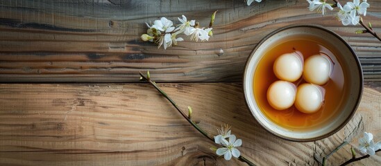 Obraz premium White tangyuan with sweet osmanthus honey and syrup in a bowl on a wooden table with copy space image.