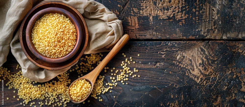 Poster top-down view of a wooden table with a bowl and spoon containing raw bulgur, ideal for adding text i