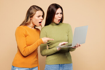 Young confused sad friend two IT women they wear orange green shirt casual clothes together hold...