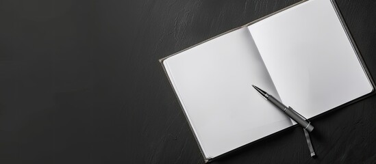 Top view of open blank notebook with a grey pen on a black background, featuring a blank space image on the right for editing text. image with copy space