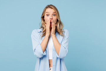 Young shocked surprised happy woman she wears white top shirt casual clothes cover mouth with hands look camera isolated on plain pastel light blue cyan background studio portrait. Lifestyle concept.