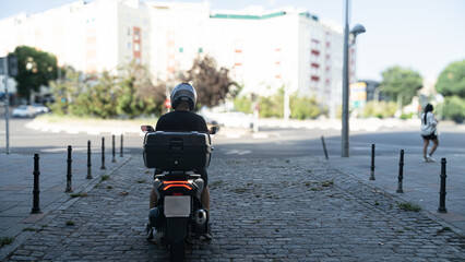 Obraz premium A man on a motorcycle is riding down a street with a building in the background