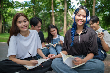 Young people is seated outdoors in a park, enjoying a collaborative study session.