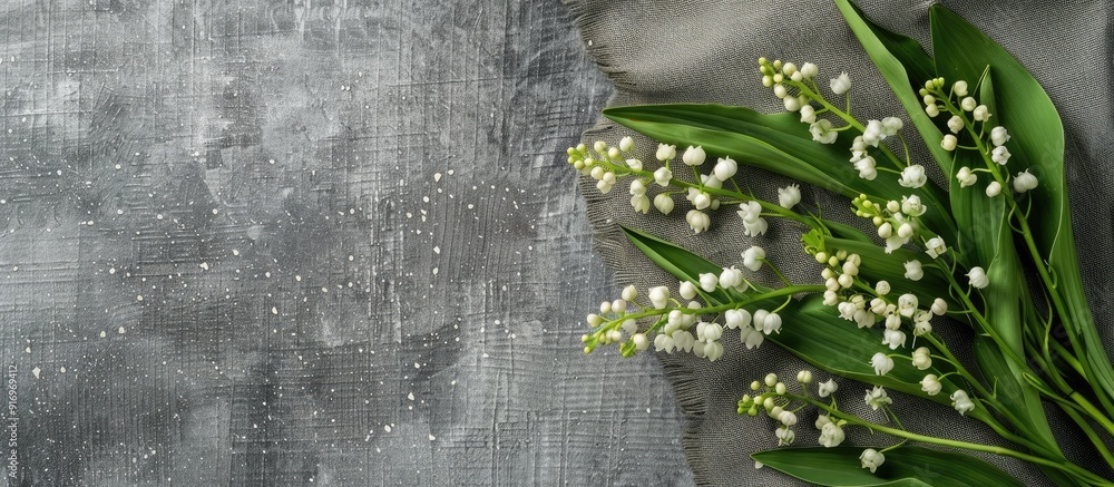 Poster top view of a rustic greeting card concept with a bouquet of white lilies of the valley and green le