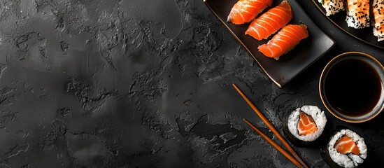 Top down shot on black backdrop showing sushi chopsticks soy sauce and copy space image
