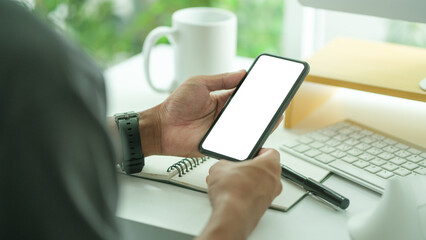 Close up view businesswoman holding smart phone and writing on notebook.
