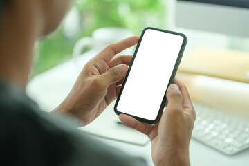 Young man holding mockup smart phone with white empty screen. Close up view.